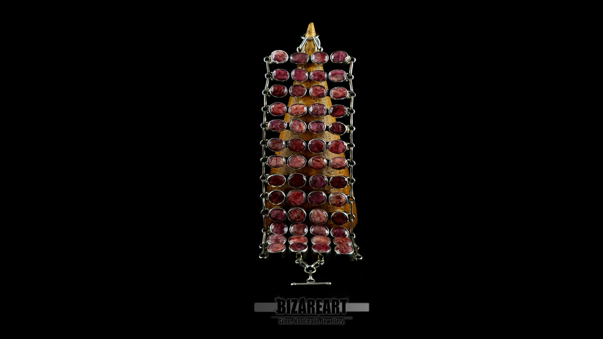 Imperium wide sterling silver armor collar with 52 hand-set raw ruby stones displayed vertically on a wooden cone against a black background.