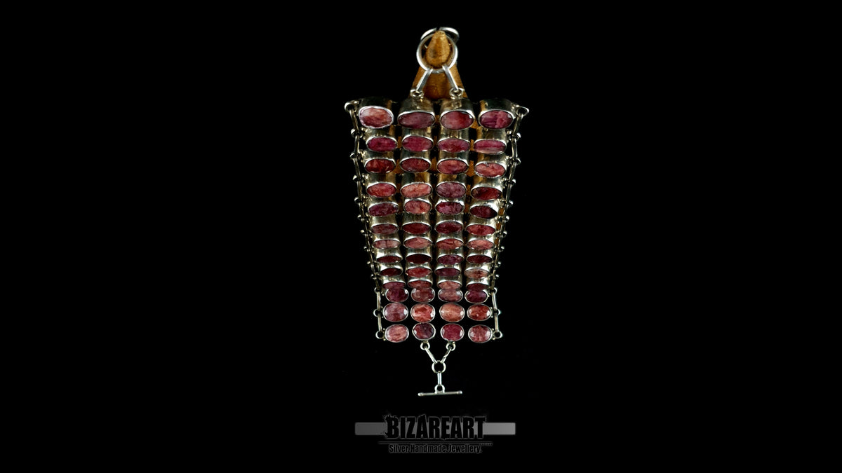 Vertical view of articulated sterling silver collar necklace showing 13 segmented rows set with natural raw ruby cabochons.