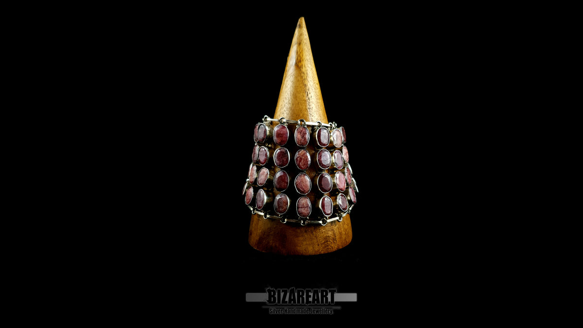 Front view of wide 140g sterling silver ruby collar draped around a wooden display cone demonstrating contouring fit.