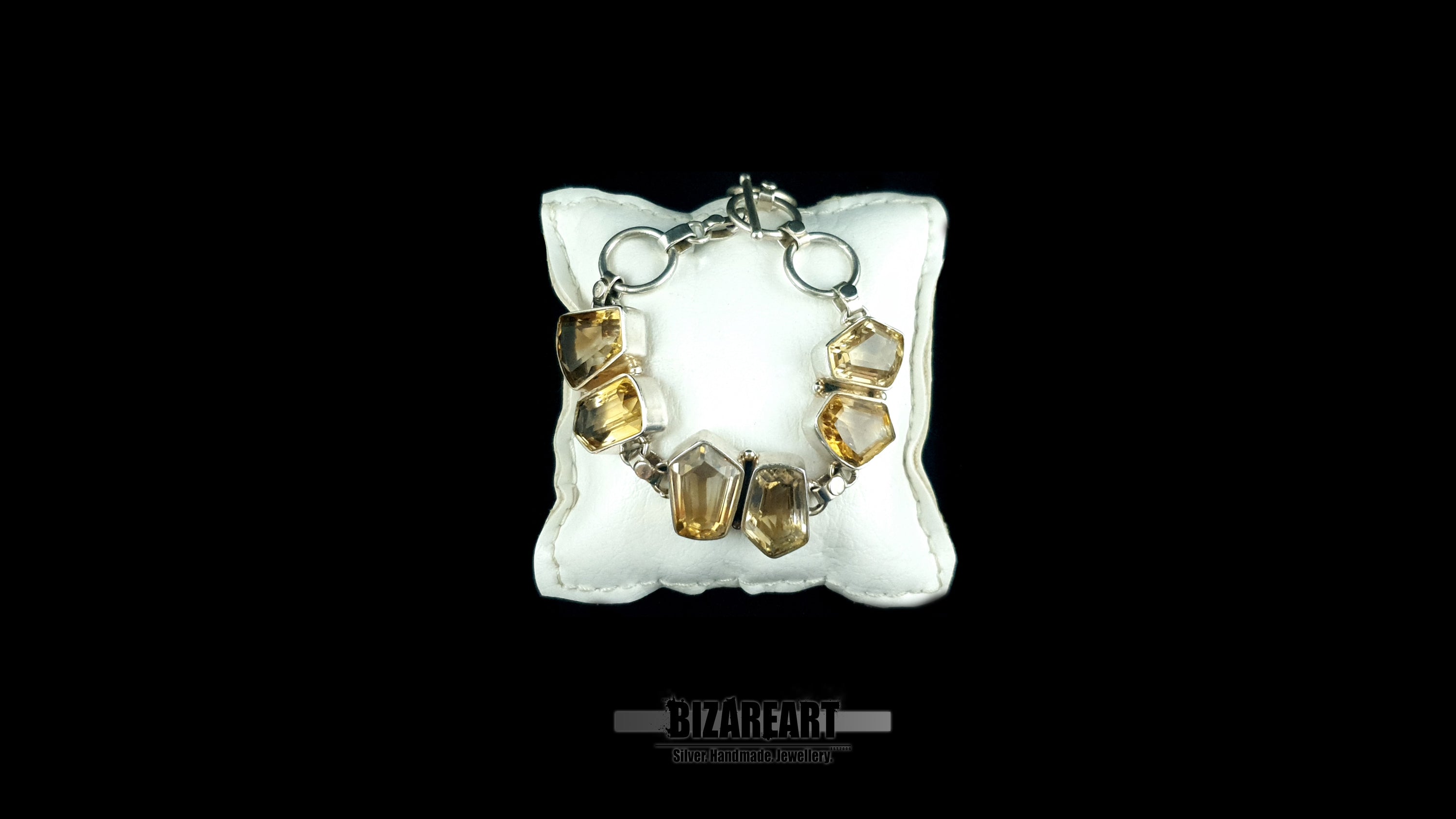 Handmade Greek silver citrine bracelet draped over a luxury white leather pillow