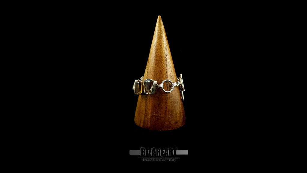 Detailed front view of silver-bezeled citrine gemstones wrapped on wooden display stand