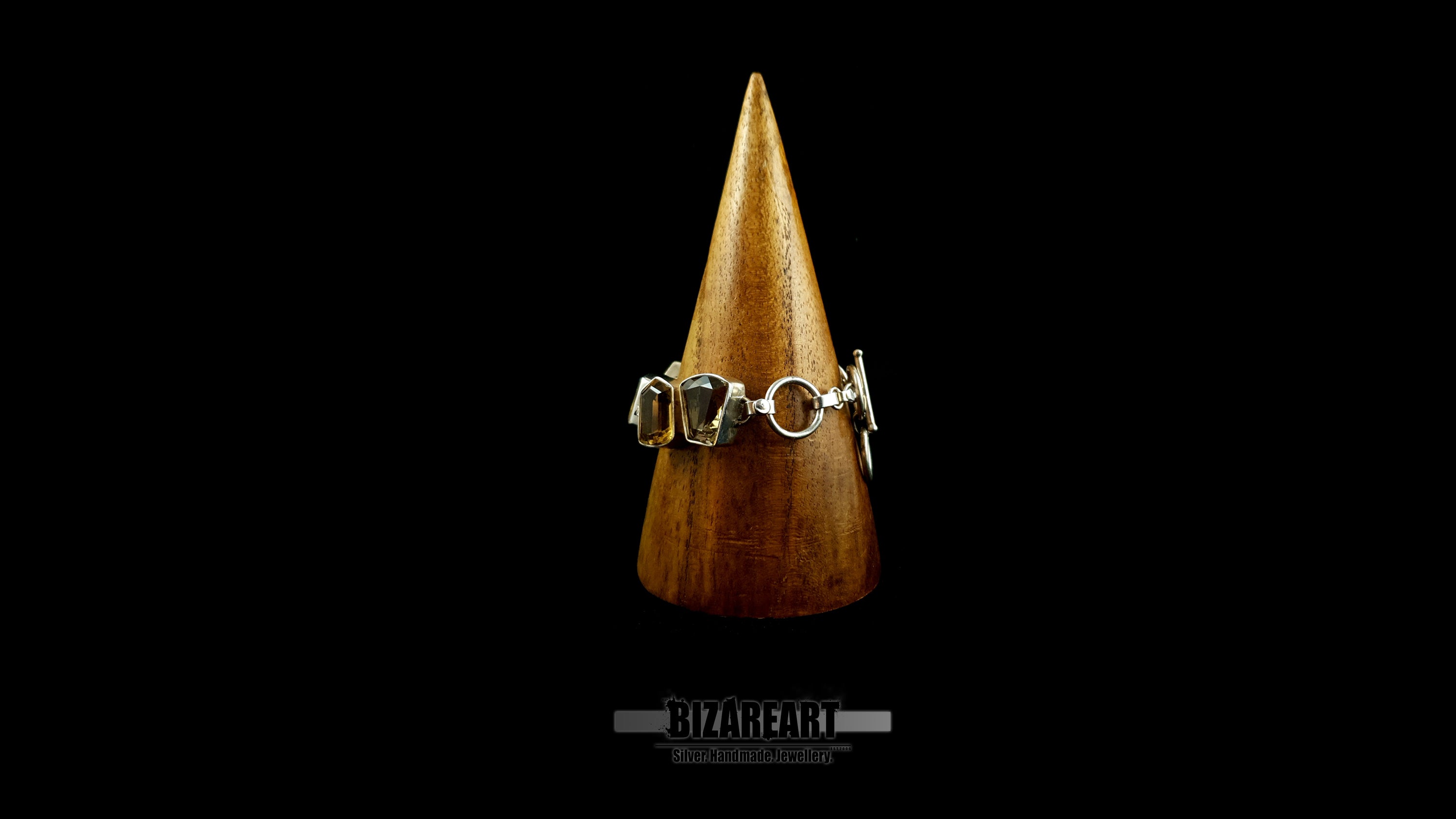 Detailed front view of silver-bezeled citrine gemstones wrapped on wooden display stand