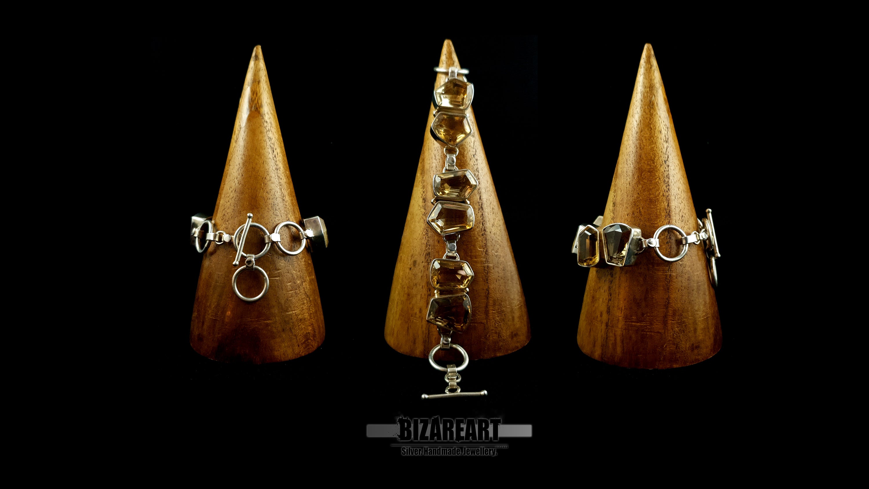 Three wooden display cones showcasing the handmade citrine silver bracelet from multiple angles