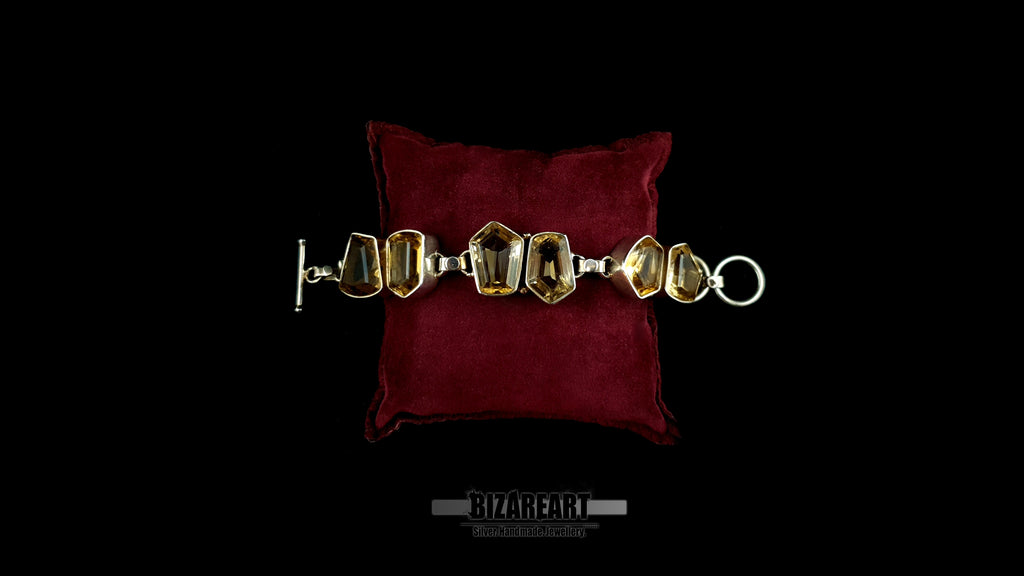 Full-length view of raw citrine silver bracelet laid open with toggle bar closure on red velvet