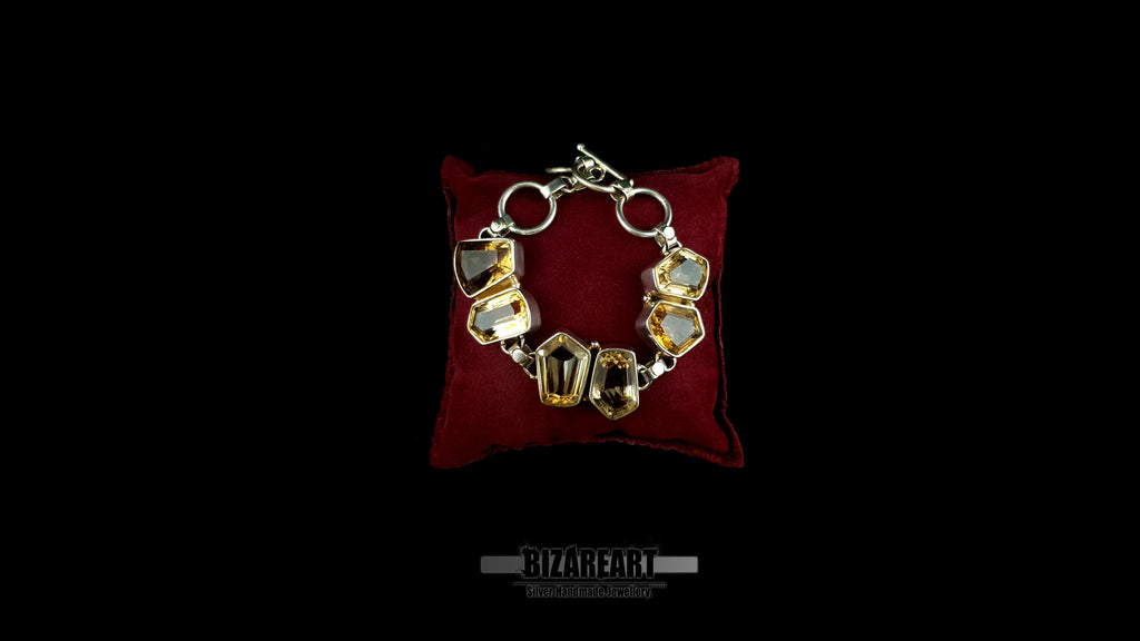 Handmade sterling silver bracelet with six raw geometric citrine gemstones displayed on red velvet pillow
