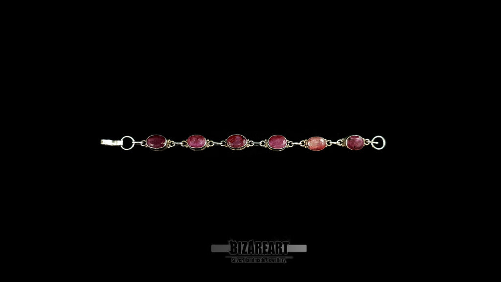 Full-length view of a 20cm handmade sterling silver chain bracelet featuring six evenly spaced raw ruby bezel settings.