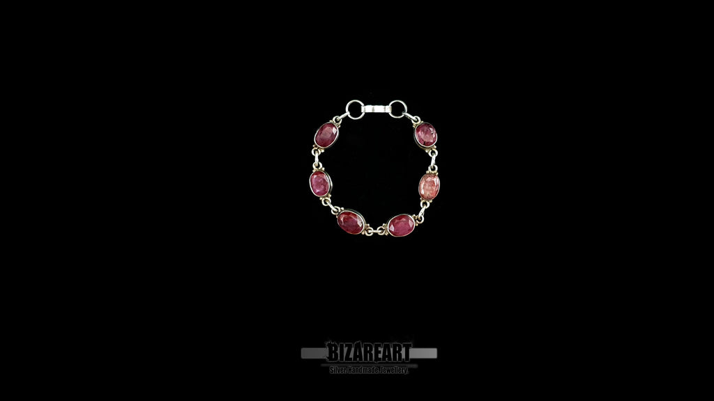 Top-down view of the Crimson Relic silver link bracelet arranged in a closed circle showcasing six oval-cut raw rubies.