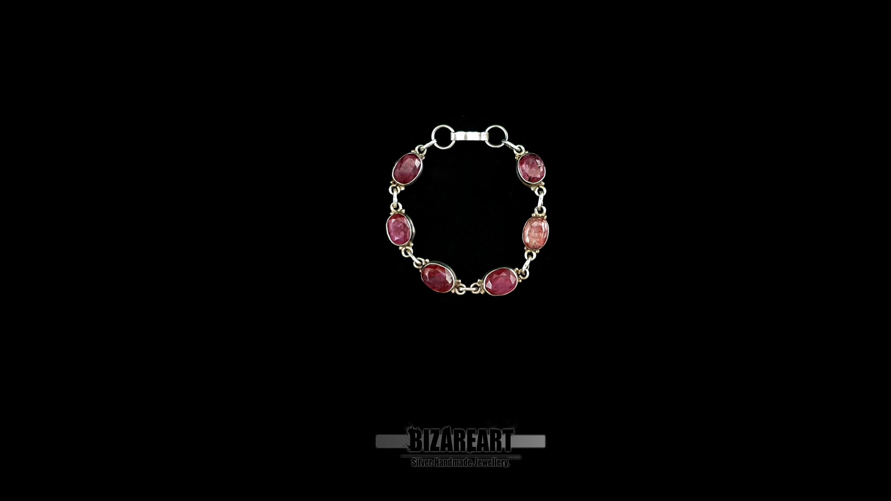 Top-down view of the Crimson Relic silver link bracelet arranged in a closed circle showcasing six oval-cut raw rubies.