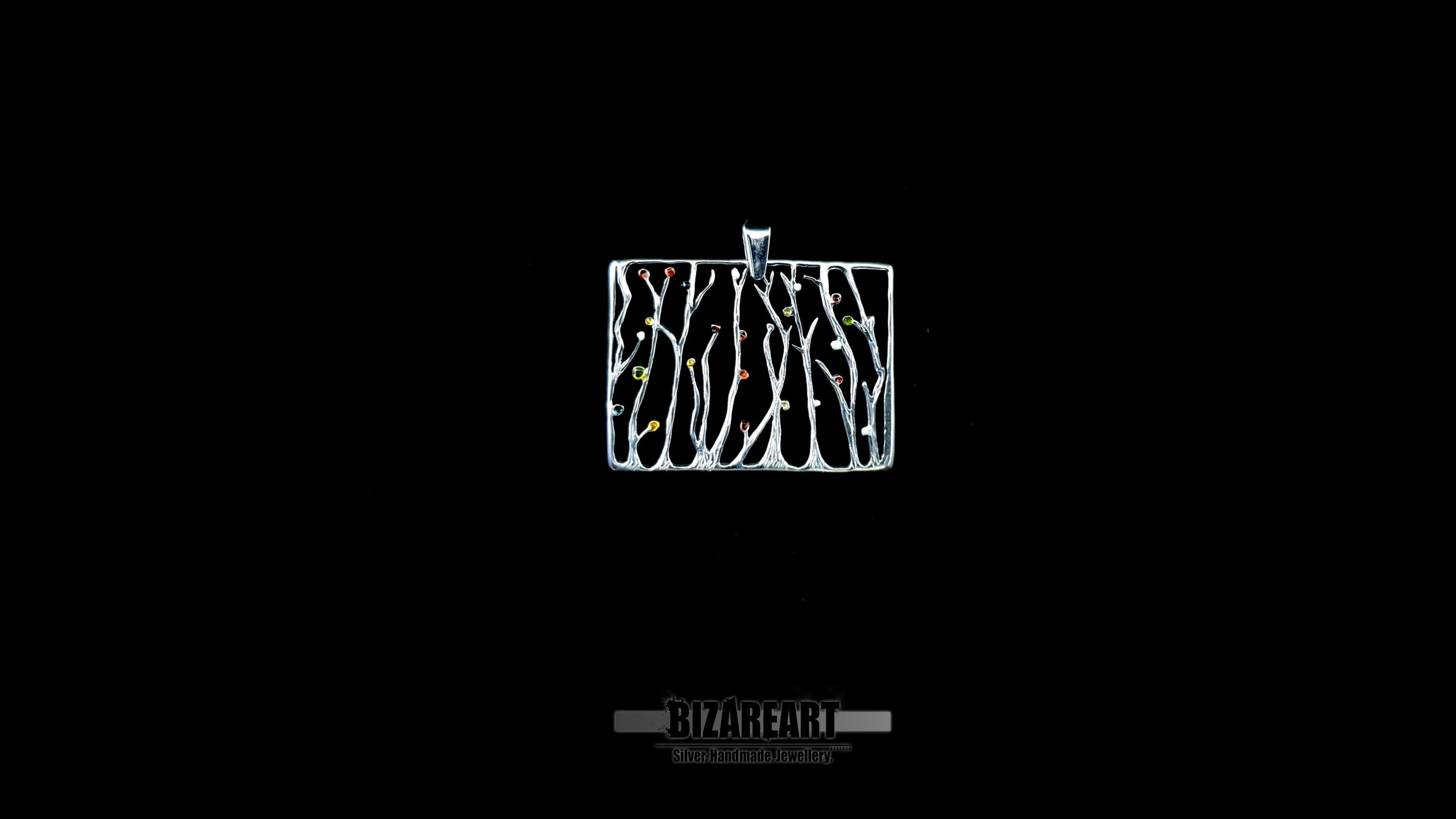 A high-contrast studio shot of the rectangular silver seaweed pendant against a solid black background, highlighting the intricate open-frame design.