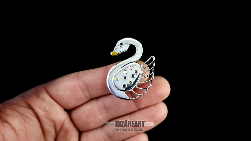 Artisan silver swan pendant held in a hand to demonstrate its 4.5 cm scale and sculptural 3D volume.