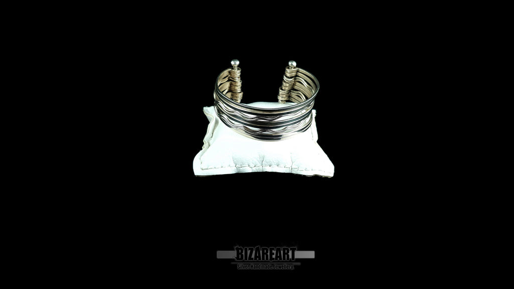 Handmade 10-strand sterling silver wave cuff bracelet with high-reflectivity mirror finish displayed on a white velvet jewelry pillow.