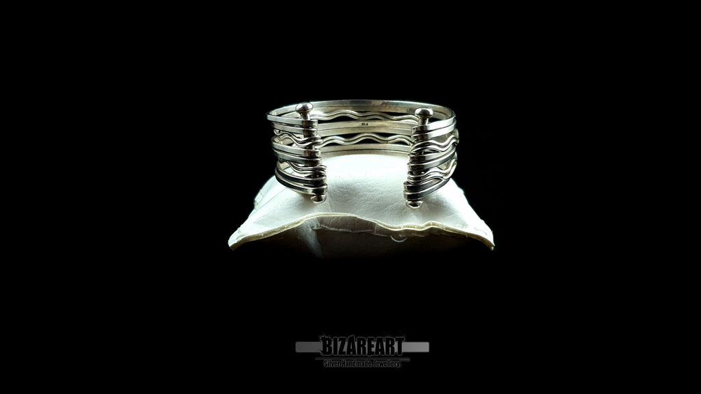 Back side view of 58.7g artisan multi-strand silver cuff showcasing the vertical ball terminal anchor bars on a white leather jewelry cushion.