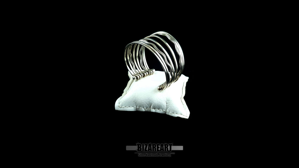 Top down angle view of 58.7g artisan multi-strand silver cuff showcasing the vertical ball terminal anchor bars on a white leather jewelry cushion.