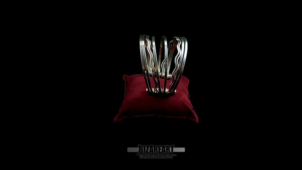 Side view of 58.7g artisan multi-strand silver cuff showcasing the vertical ball terminal anchor bars on a red leather jewelry cushion.
