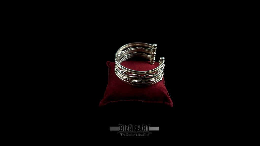 Fully handmade 10-strand sterling silver wave cuff bracelet with high-reflectivity mirror finish displayed on a red velvet jewelry pillow.
