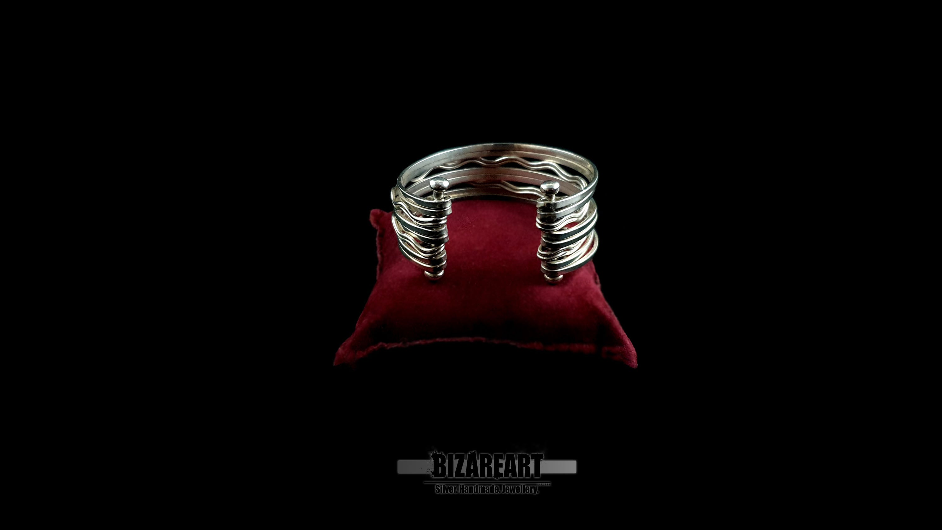 Handmade 10-strand sterling silver wave cuff bracelet with high-reflectivity mirror finish displayed on a red velvet jewelry pillow.