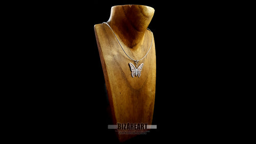Hand-cut silver butterfly pendant hanging on a silver chain displayed on a wooden jewelry bust.