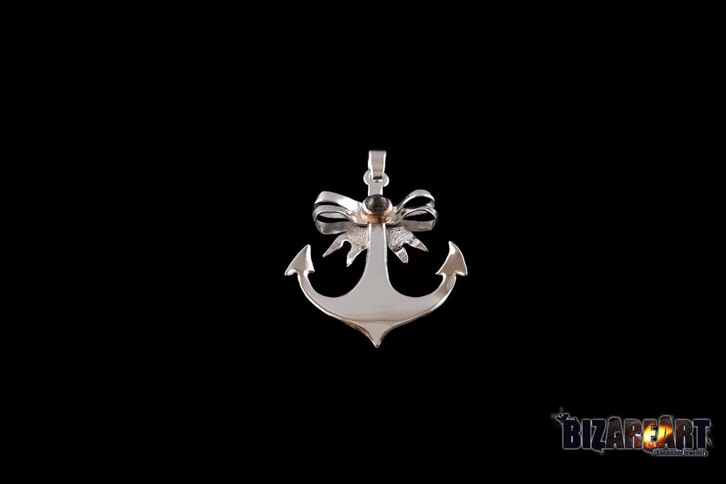 A high-resolution studio shot of the Anchor Pendant against a solid black background. The pendant features a polished 925 sterling silver anchor body topped with a delicate rose-plated copper bow and a central bi-color tourmaline gemstone.