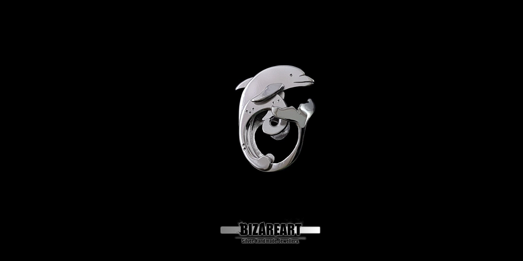 A high-contrast studio shot of a 3D sterling silver dolphin pendant featuring a unique layered design, shown centered against a solid black background with the "BIZAKEART" logo below.
