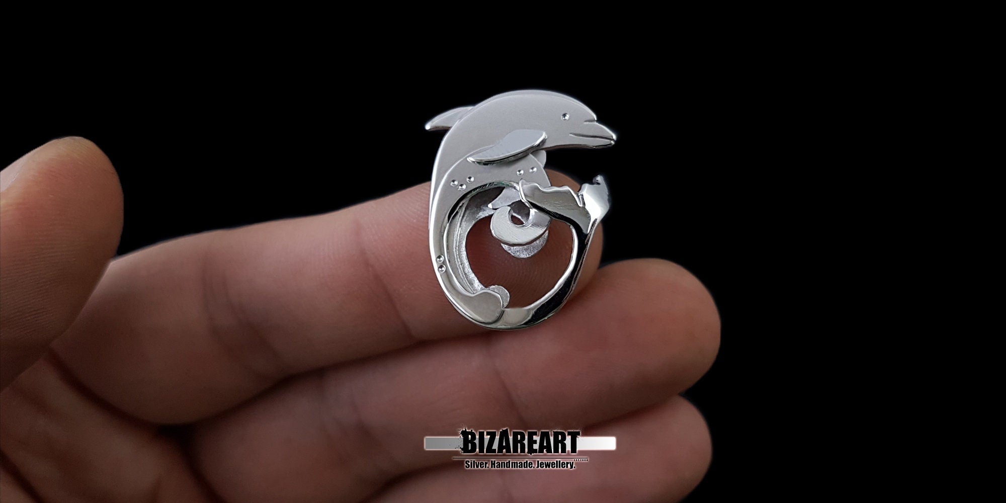 Front-facing view of the artisan dolphin jewelry, showcasing the elegant play of light across the bright and brushed silver surfaces.