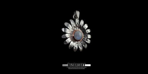 Studio shot of the artisanal mixed-metal daisy pendant, showcasing the contrast between the hammered silver petals and the warm copper accent around the gemstone.