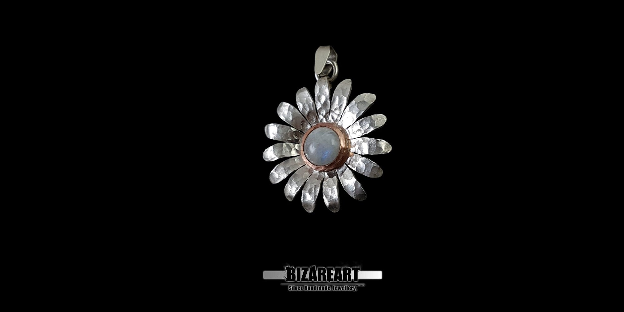 Close-up of a handcrafted 925 sterling silver flower pendant with a central moonstone cabochon, highlighting the rustic, raw texture of the background finish.
