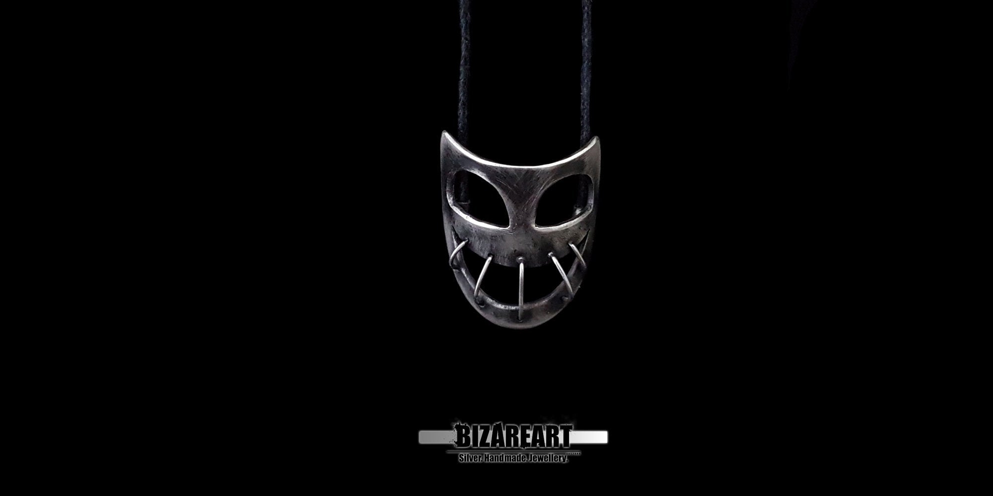 Close-up view of the alternative style sterling silver mask pendant, showcasing the raw matte texture and carved details