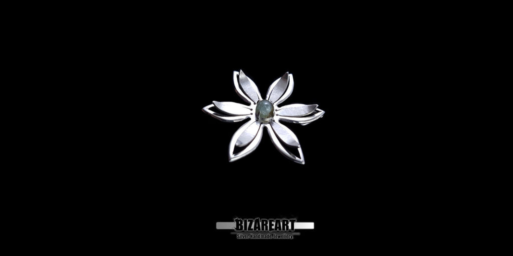 A series of product photography shots showing the silver flower pendant from various angles on a black background, highlighting the metallic sheen and the depth of the central gemstone.