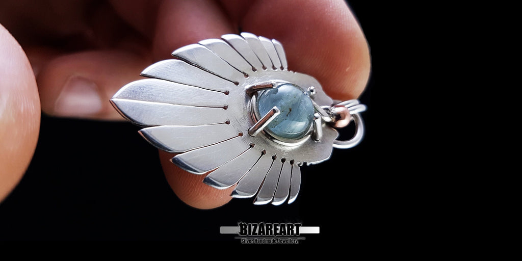 Lifestyle close-up of the Silver Wings Pendant held in hand to provide a scale reference, emphasizing the bright and matte brushed finish.