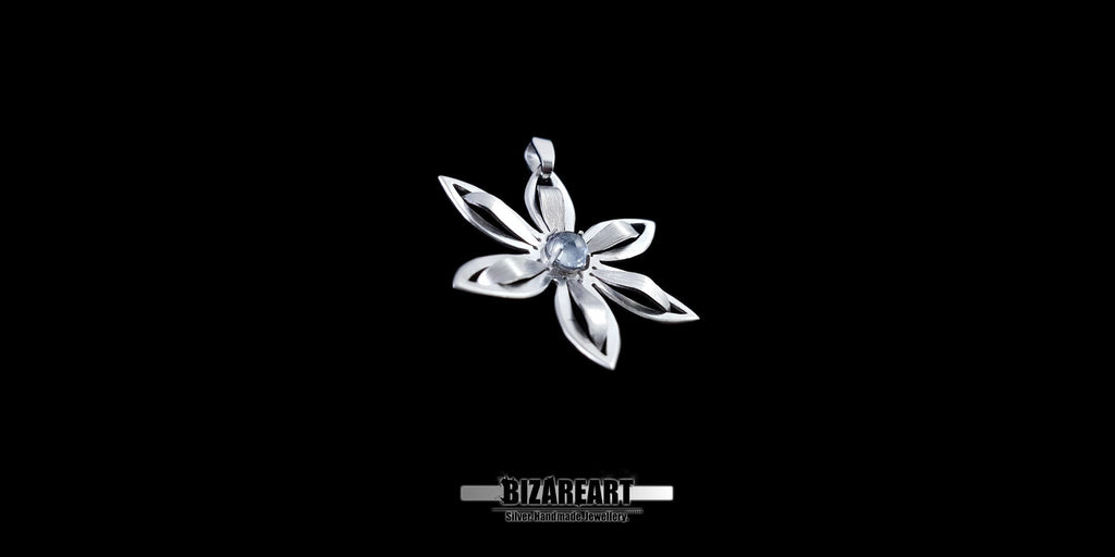 Silver flower-shaped pendant with a central gemstone on a black background
