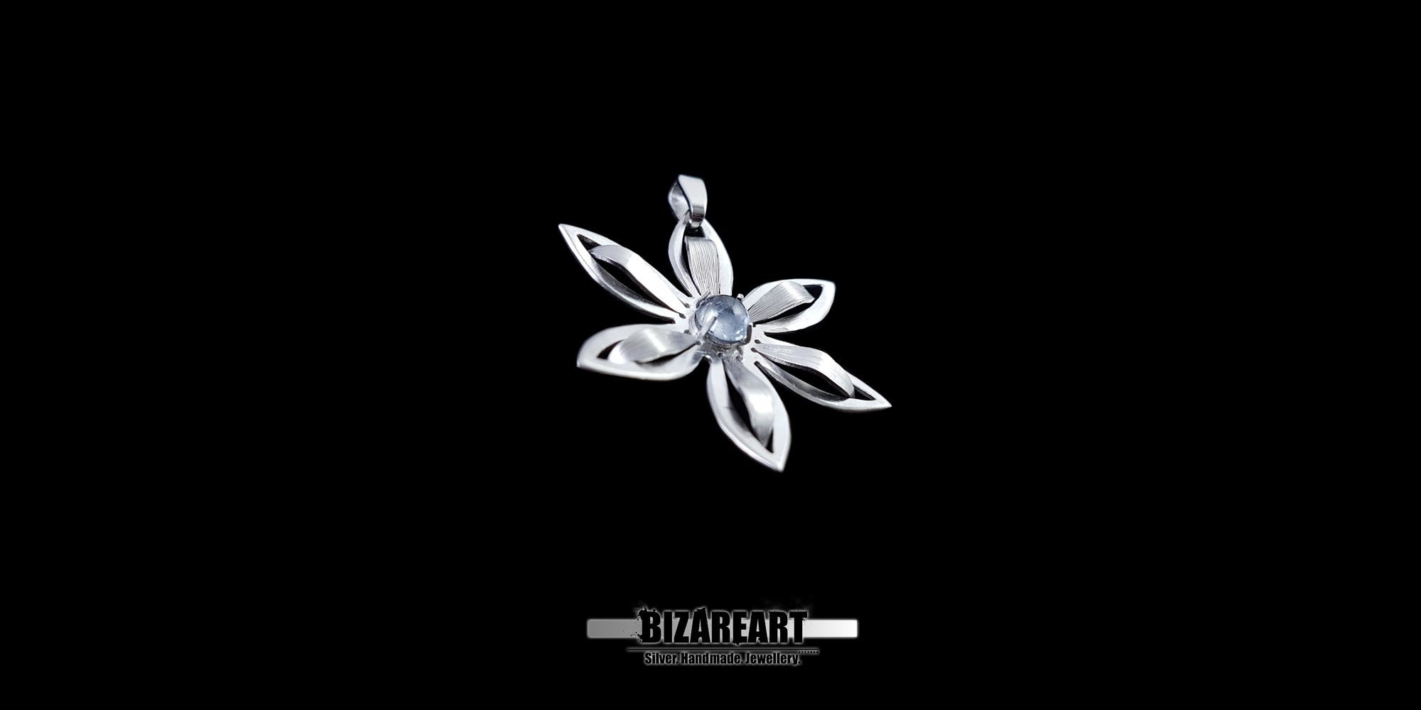 Silver flower-shaped pendant with a central gemstone on a black background