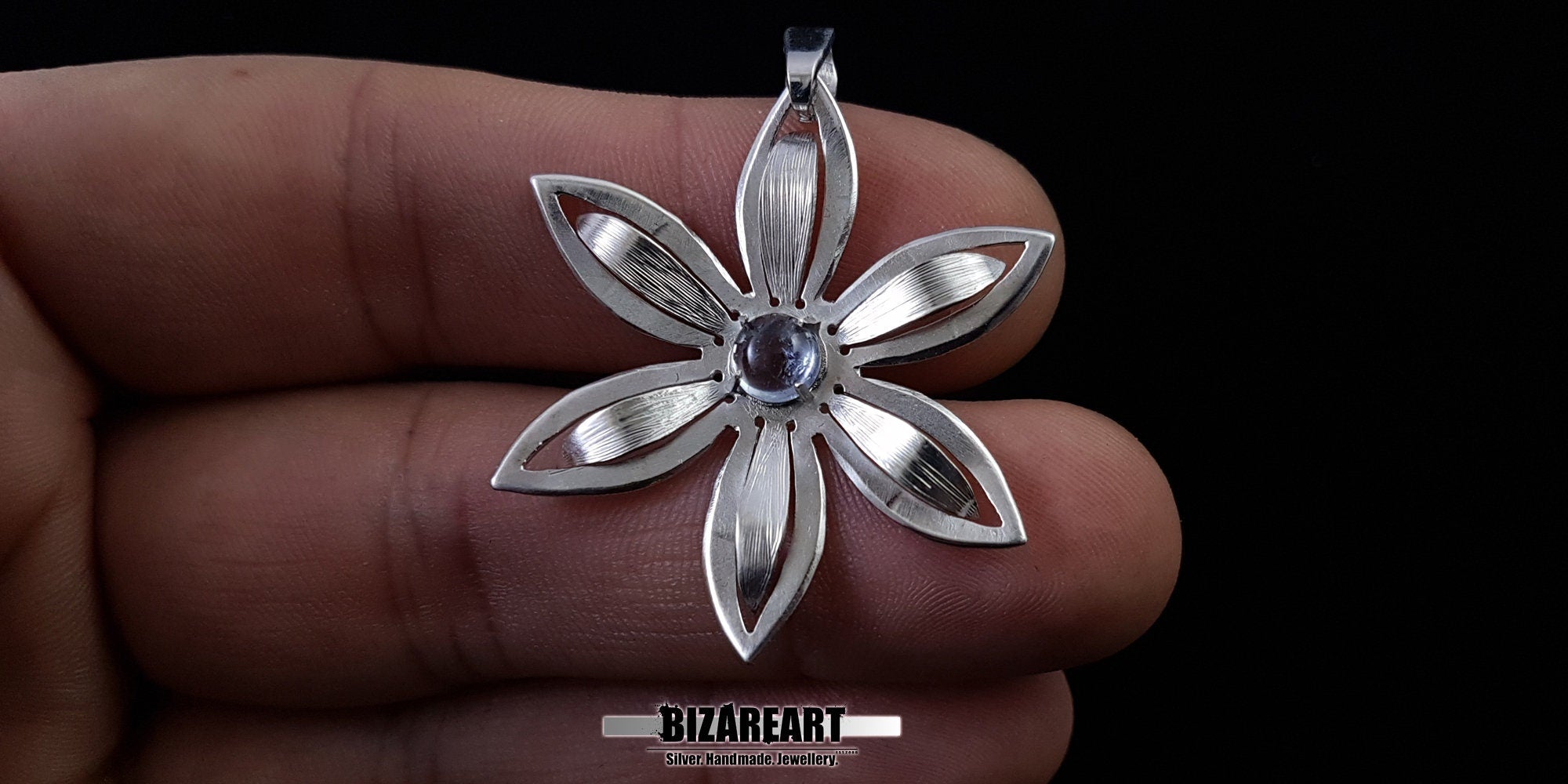 Handcrafted silver flower pendant held in hand to demonstrate the 4cm size and scale.