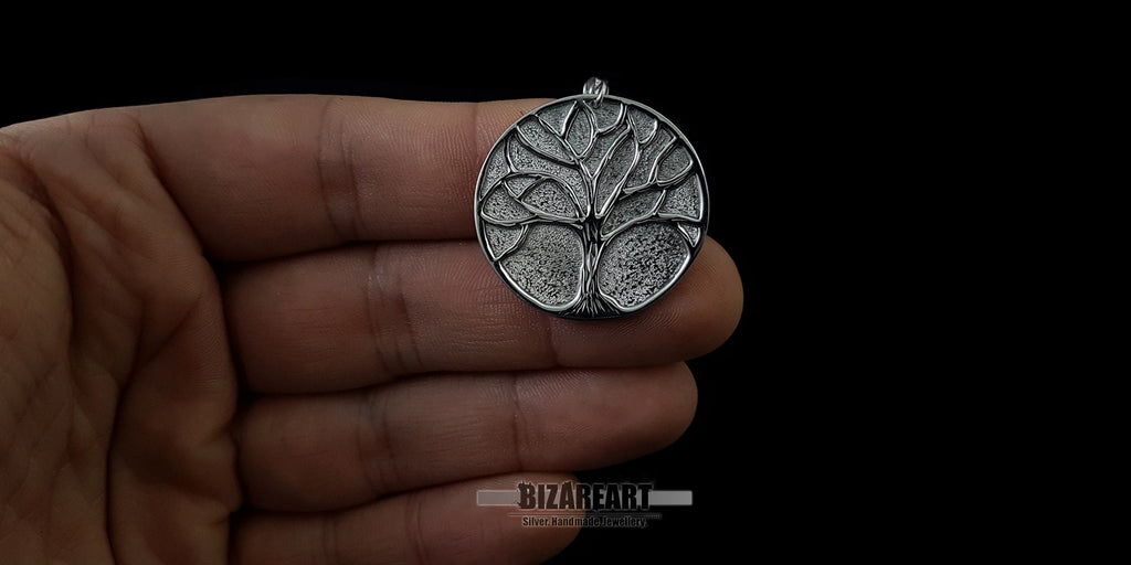 Hand held of the oxidized tree pendant showing the handcrafted silver textures and sizing