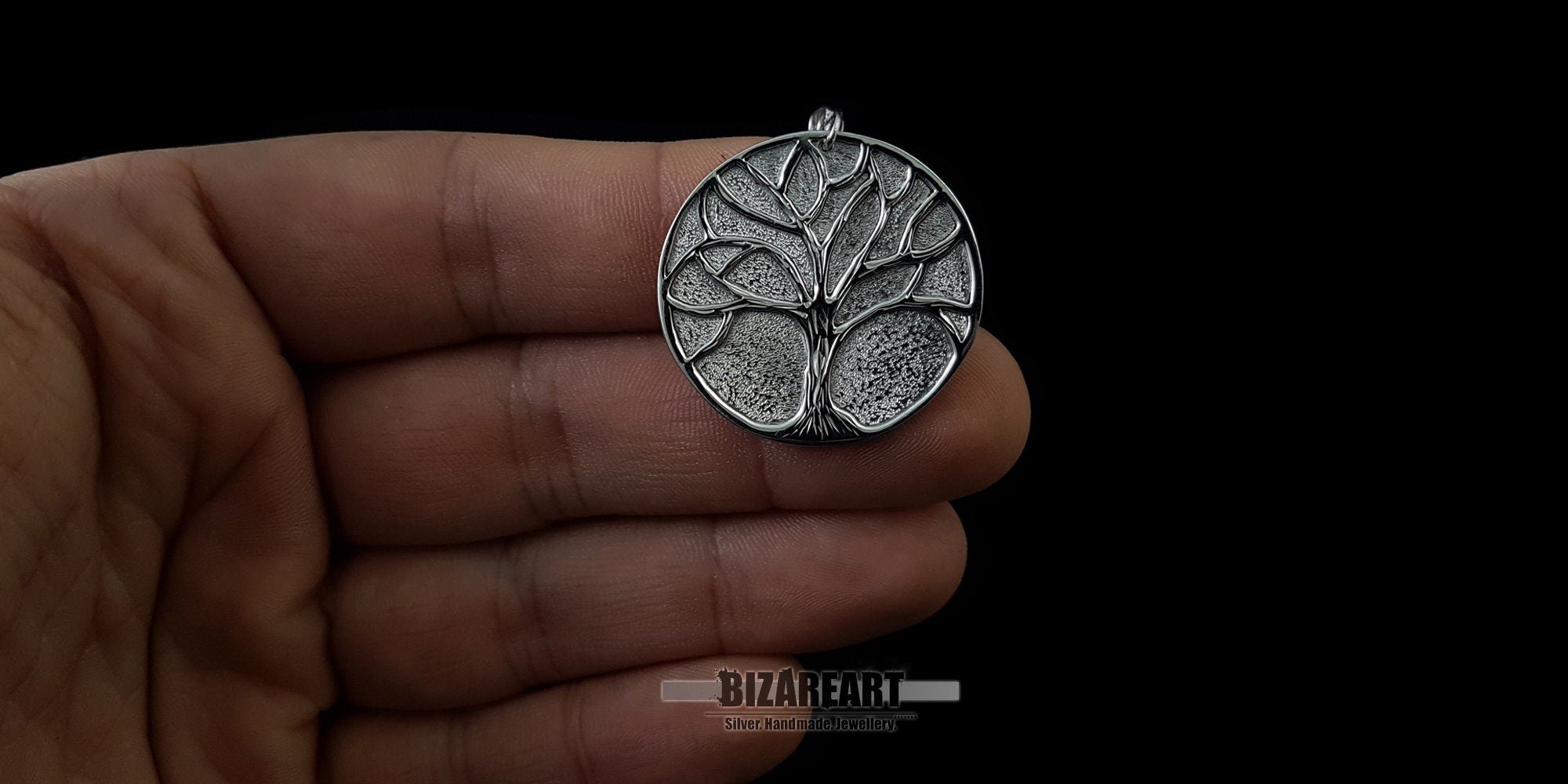 Hand held of the oxidized tree pendant showing the handcrafted silver textures and sizing
