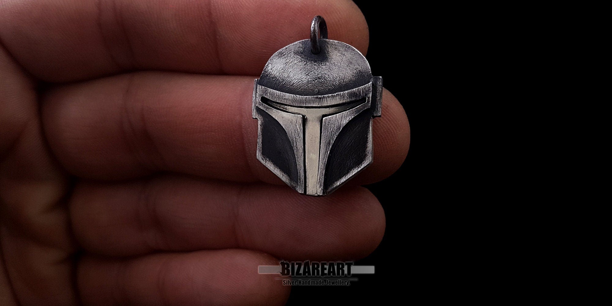 A hand holding the 7.7g oxidized sterling silver warrior helmet pendant, providing a realistic size reference for daily wear.