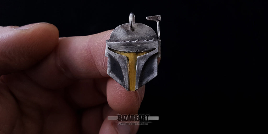 A close-up shot of a hand holding the 925 sterling silver Boba Fett pendant to show its actual size and scale.
