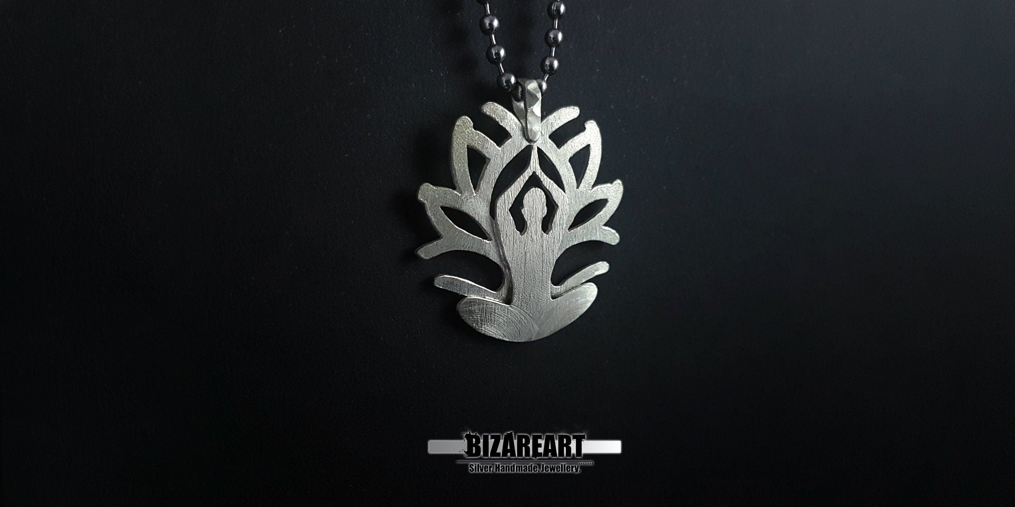 A close-up side angle of the pendant held in a hand, showcasing the "Inner Bloom" yoga figure integrated into the petal design.
