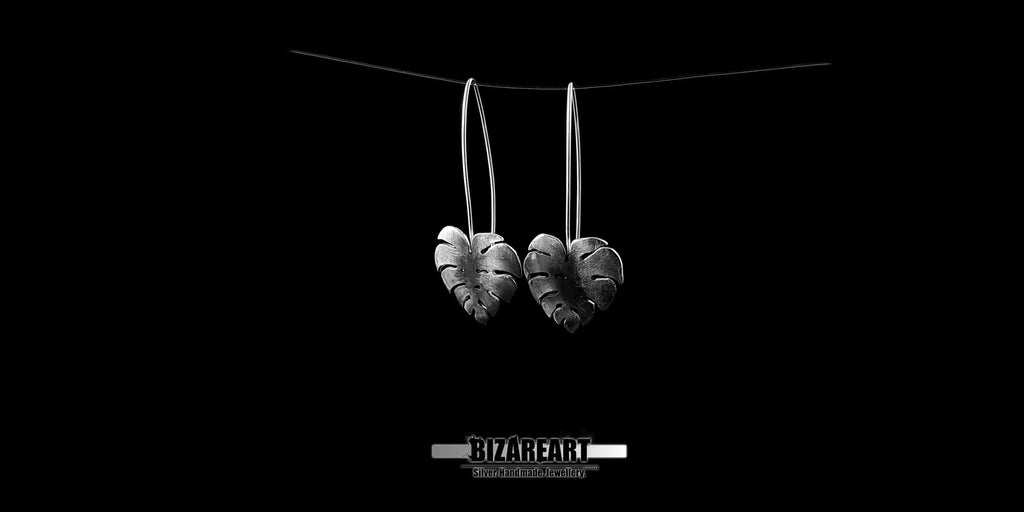 A close-up view of the earrings resting on palms, revealing the artisan craftsmanship and the vintage, antique silver finish.