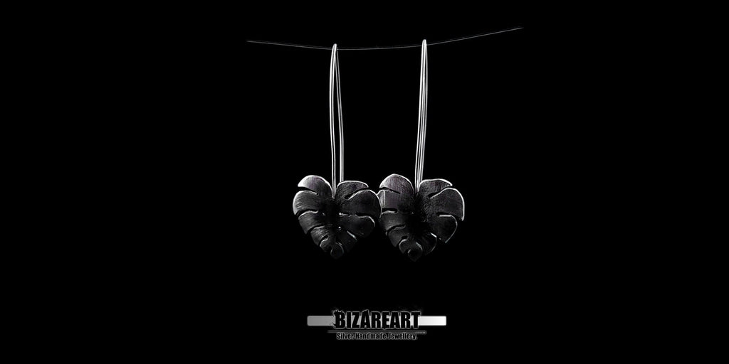 Monstera leaf earrings held in a hand to demonstrate the true size and proportions of the 6.2g solid silver pieces.