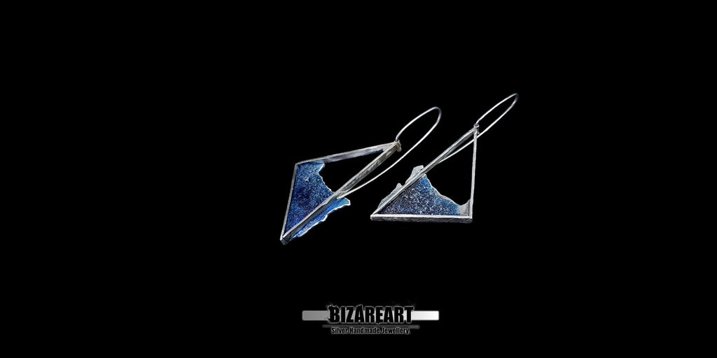 Flat lay of the handmade asymmetric silver beach earrings displaying the unique differences between the left and right pieces.