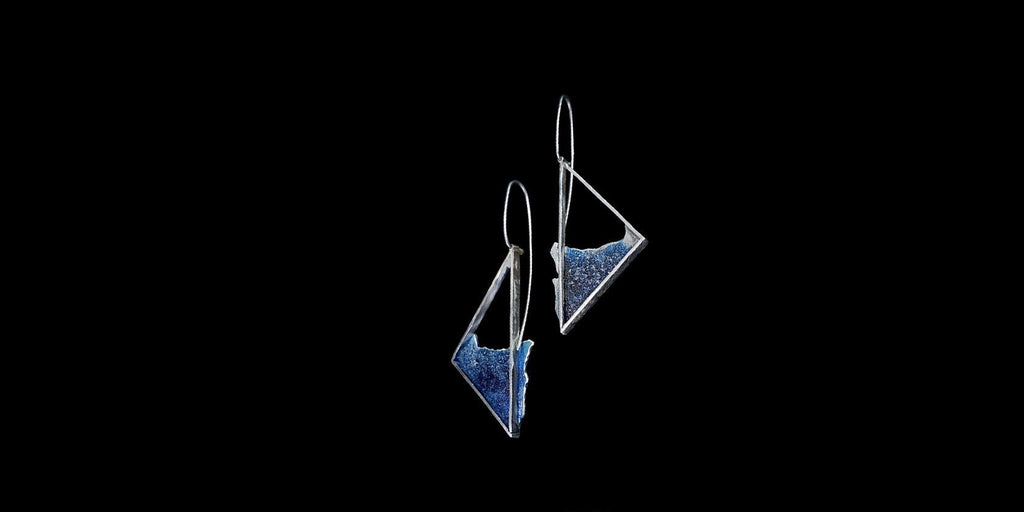 Side view of the silver dangle earrings highlighting the textured windy swirl pattern and sculptural, free-swinging design.