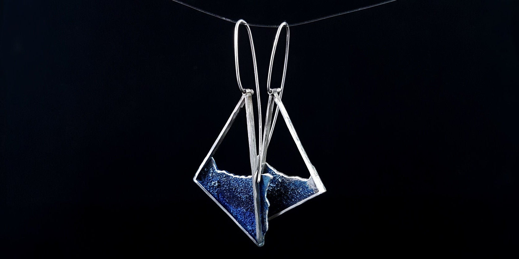 Pair of handmade .925 silver triangle earrings showcasing the geometric frame design and ocean wave enamel details.