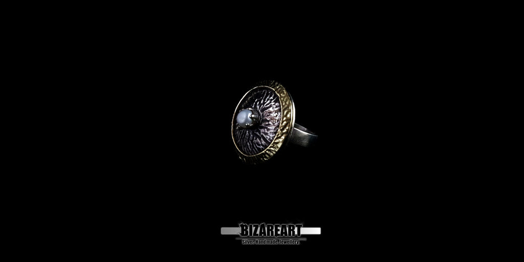 Perspective view showing the depth of the ring's engraved edges and the rough-hewn texture of the silver foreground.