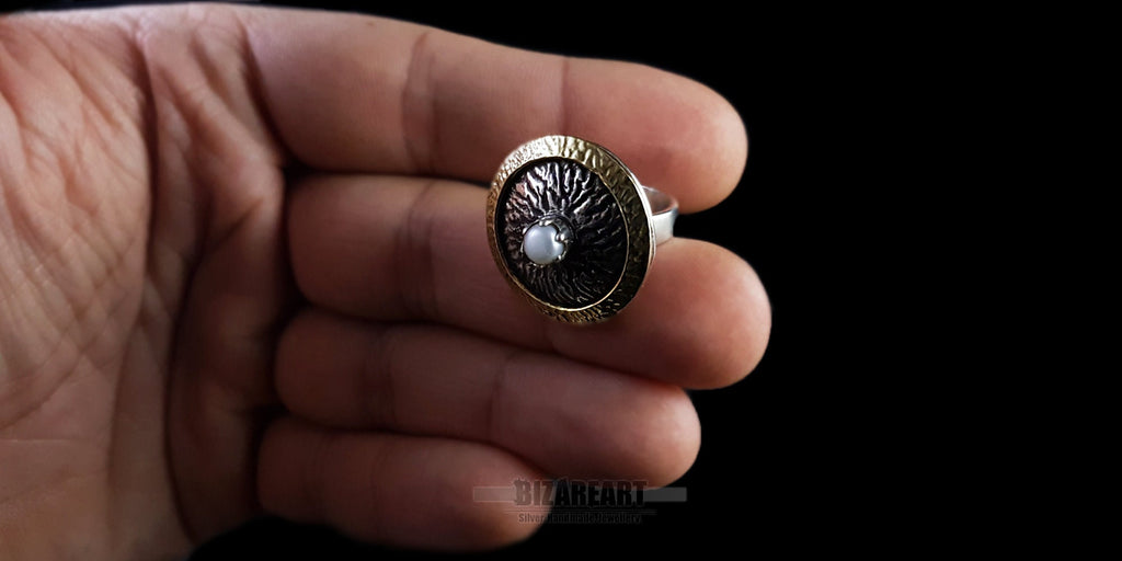 Hand-held scale shot of the Bromo Ring resting between fingers to demonstrate its real-world size and sculptural presence.