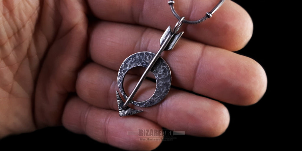 Close-up lifestyle detail of the pendant being held, showing the texture of the 925 sterling silver under natural lighting.