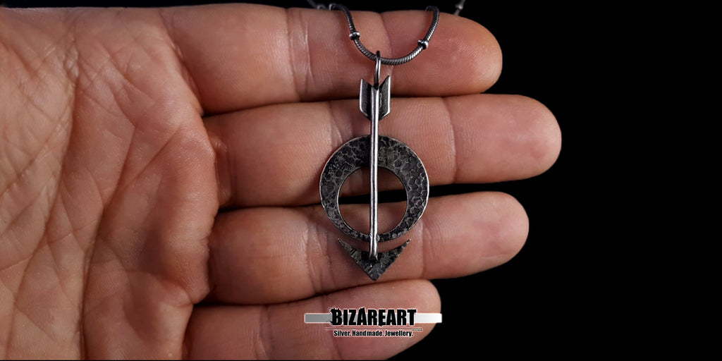Lifestyle shot of the Silver Moon Arrow Pendant held in a person's palm to demonstrate scale and size.