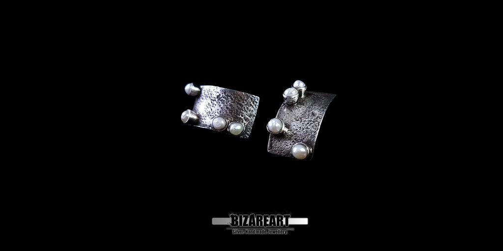 Flat lay of the pearl and silver earrings against a black background, emphasizing the geometric rectangular silhouette.