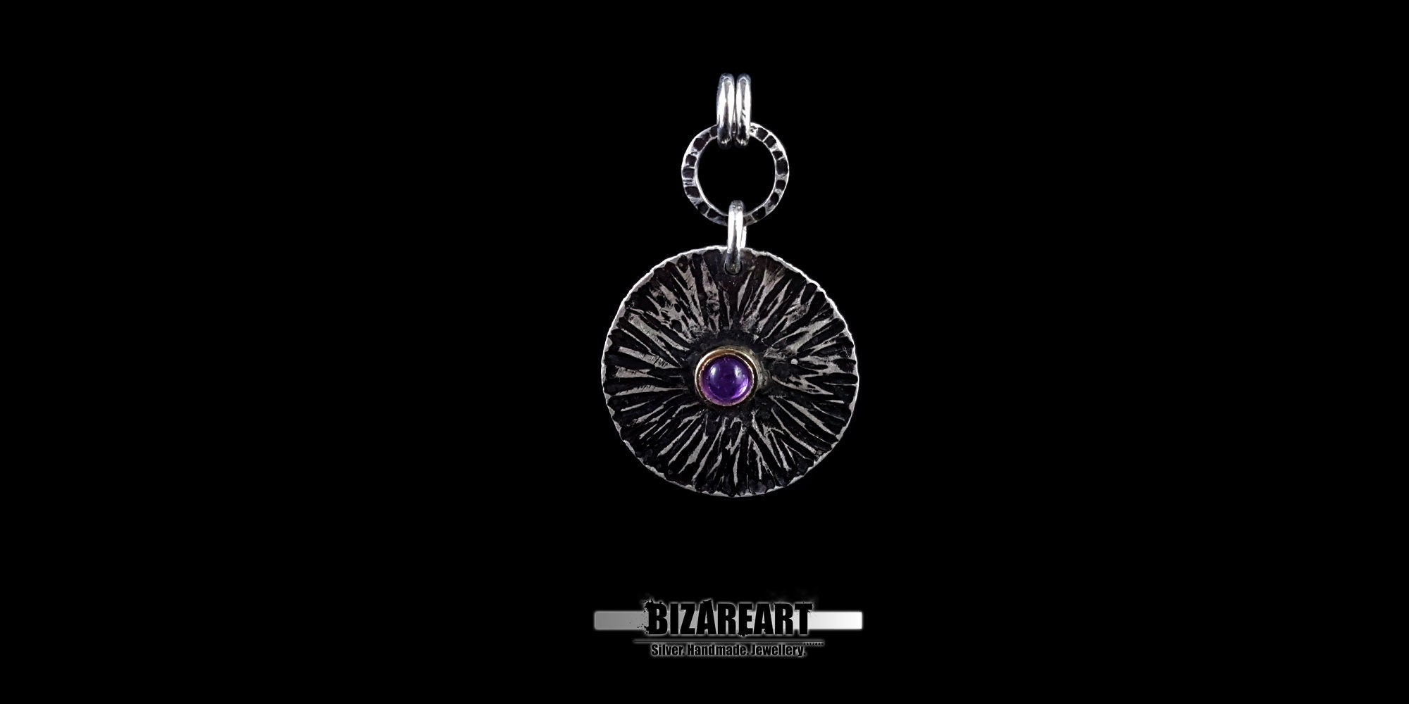 Front view of the Bromo Charm pendant featuring radial "Sea of Sand" etchings and a central amethyst stone set in a bronze bezel.