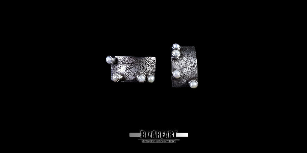 Side-by-side view of artisan silver studs showing the unique dimpled metal pattern and secure pearl settings.