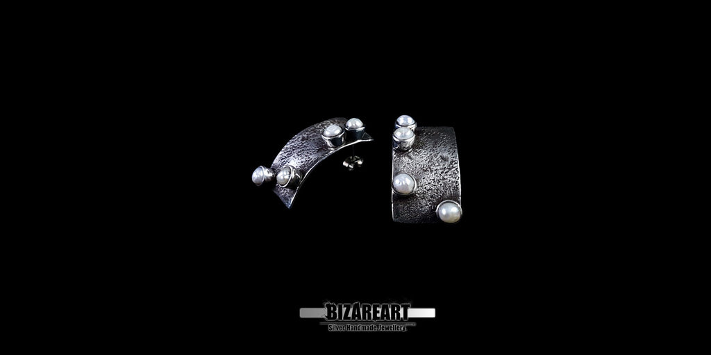 View of the subtle backward bend and sculptural profile of the oxidized sterling silver earrings.